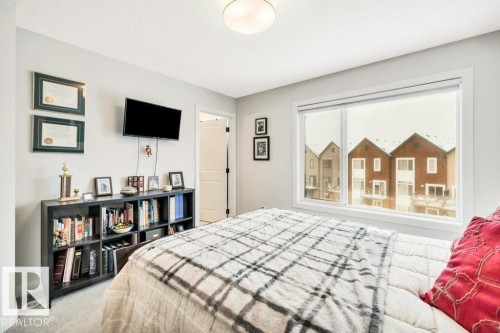 This room features light-colored walls and a window with a view of red brick structures - 99 1010 Rabbit Hill Road, Edmonton, AB - Indoor Photo Showing Bedroom