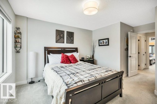 This room features light-colored carpeting, a window providing natural light, and a ceiling-mounted light fixture - 99 1010 Rabbit Hill Road, Edmonton, AB - Indoor Photo Showing Bedroom