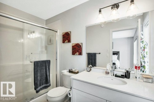 Bathroom featuring a vanity with a white countertop and an integrated sink, a large mirror, and a shower with a sliding glass door - 99 1010 Rabbit Hill Road, Edmonton, AB - Indoor Photo Showing Bathroom