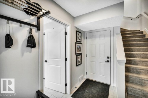 Entryway featuring a staircase with carpeted treads and a white banister, alongside a white paneled door with black hardware - 99 1010 Rabbit Hill Road, Edmonton, AB - Indoor Photo Showing Other Room