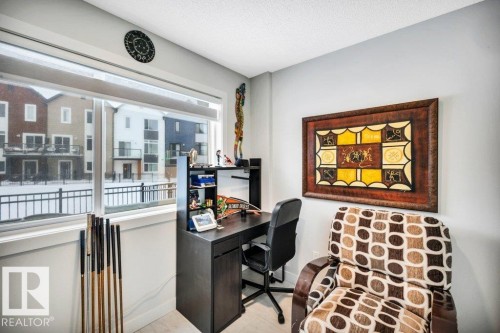 This bright room features a large window, offering views of the surrounding properties and a black metal fence - 99 1010 Rabbit Hill Road, Edmonton, AB - Indoor Photo Showing Other Room