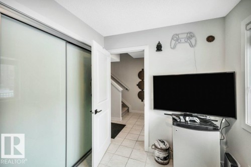 This area features light-colored tile flooring, a white paneled door, and a sliding door with frosted glass panels - 99 1010 Rabbit Hill Road, Edmonton, AB - Indoor Photo Showing Other Room