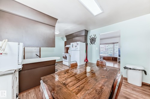 The kitchen features a wooden dining table, white appliances, and brown cabinetry - 4237 116 Avenue, Edmonton, AB - Indoor Photo Showing Dining Room