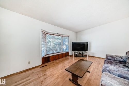 The interior features light-colored hardwood flooring and a bay window with integrated storage - 4237 116 Avenue, Edmonton, AB - Indoor Photo Showing Living Room