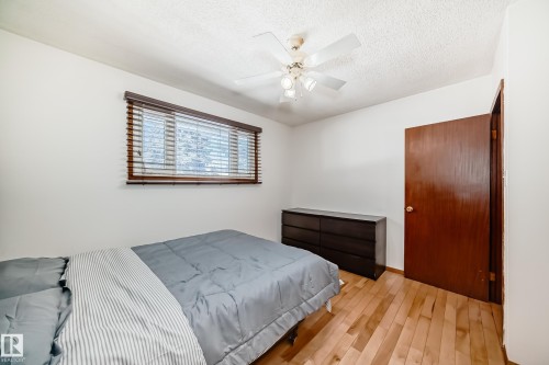This room features hardwood floors, a window with horizontal blinds, and a ceiling fan with a light fixture - 4237 116 Avenue, Edmonton, AB - Indoor Photo Showing Bedroom