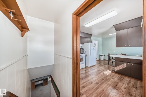 The property includes a kitchen with dark cabinetry, light countertops, and wood-look flooring - 4237 116 Avenue, Edmonton, AB - Indoor Photo Showing Other Room