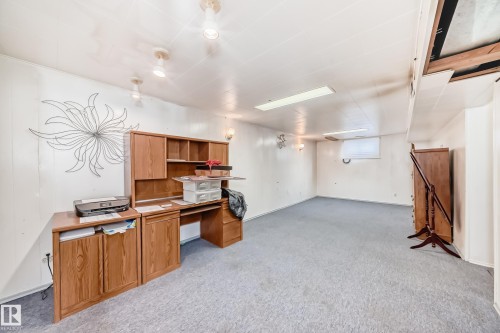 The property features a spacious room with light-colored carpeting, white walls, and track lighting on the ceiling - 4237 116 Avenue, Edmonton, AB - Indoor