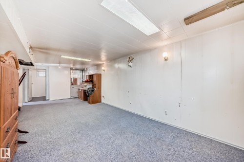 Spacious interior room featuring light blue carpeting, white paneled walls, and overhead lighting - 4237 116 Avenue, Edmonton, AB - Indoor