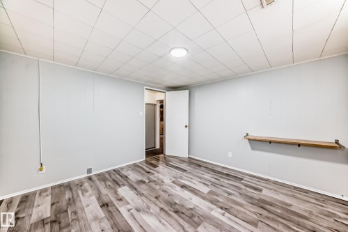 The property features a spacious room with wood-look flooring, light-colored walls, and a recessed ceiling - 4237 116 Avenue, Edmonton, AB - Indoor Photo Showing Other Room