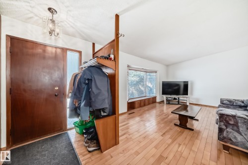 Entryway and living area featuring hardwood flooring, a large bay window with a built-in bench, and a warm wood entry door with a sidelight - 4237 116 Avenue, Edmonton, AB - Indoor