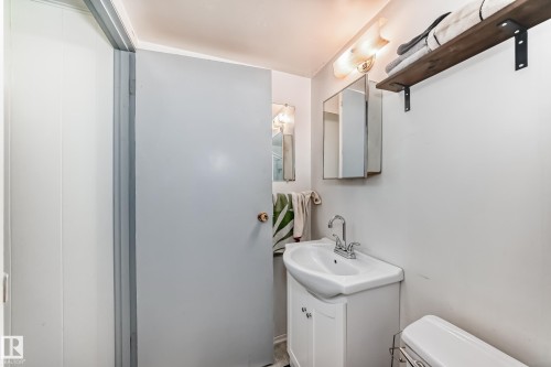 The bathroom features a white vanity with a rectangular sink, a wall-mounted medicine cabinet, and a wooden shelf with metal brackets - 4237 116 Avenue, Edmonton, AB - Indoor Photo Showing Bathroom