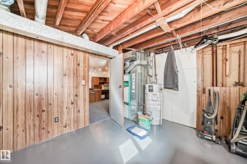 This utility area features an exposed wood beam ceiling, wood paneling, and a painted concrete floor - 4237 116 Avenue, Edmonton, AB - Indoor Photo Showing Basement