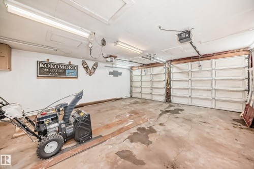 The property features a garage with two overhead doors and fluorescent lighting - 4237 116 Avenue, Edmonton, AB - Indoor Photo Showing Garage