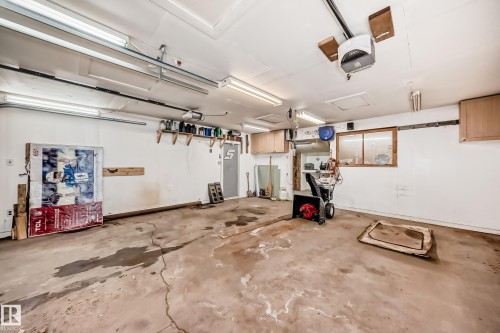 Spacious garage with overhead lighting, a garage door opener, and a window for natural illumination - 4237 116 Avenue, Edmonton, AB - Indoor Photo Showing Garage