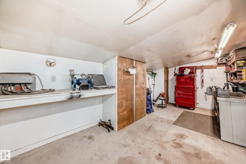 This functional workspace features a concrete floor, built-in shelving, and overhead lighting - 4237 116 Avenue, Edmonton, AB - Indoor