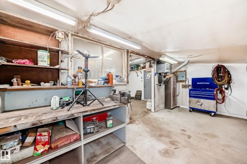 Workshop space featuring concrete flooring, fluorescent lighting, and a built-in workbench with shelving - 4237 116 Avenue, Edmonton, AB - Indoor