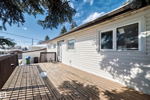 The property features a wooden deck with railing, a white vinyl-sided exterior, and white-framed windows - 4237 116 Avenue, Edmonton, AB - Outdoor