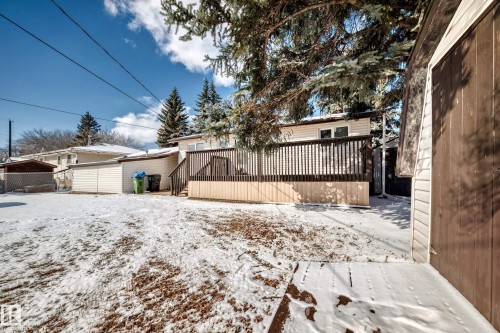 The property features a spacious deck with wood railings and steps, overlooking a yard with visible ground cover - 4237 116 Avenue, Edmonton, AB - Outdoor
