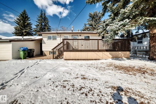 The property features a rear exterior with horizontal siding, a wooden deck with railing and stairs, and a visible exterior door - 4237 116 Avenue, Edmonton, AB - Outdoor