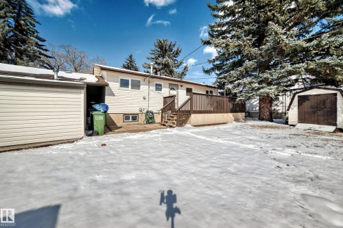 The property features a rear deck with wooden railings and stairs, a detached garage, and an additional shed - 4237 116 Avenue, Edmonton, AB - Outdoor