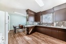 The kitchen features wood-look flooring, brown cabinetry, a white countertop, and a tiled backsplash - 4237 116 Avenue, Edmonton, AB  - Indoor 