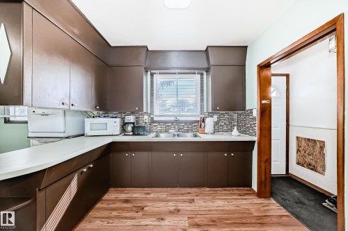 The kitchen features brown cabinetry, light-colored countertops, and a tiled backsplash - 4237 116 Avenue, Edmonton, AB - Indoor Photo Showing Kitchen With Double Sink