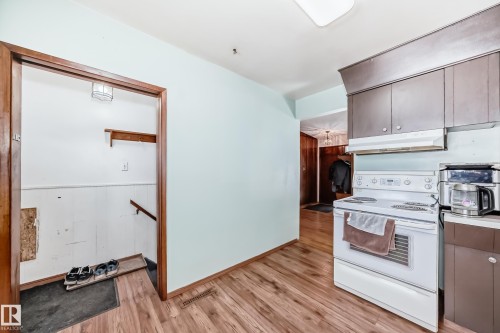 This kitchen features wood-look flooring, light blue walls, and dark brown cabinetry - 4237 116 Avenue, Edmonton, AB - Indoor Photo Showing Kitchen