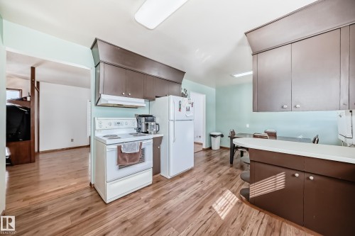 Kitchen featuring wood-look flooring, brown cabinetry, and white appliances - 4237 116 Avenue, Edmonton, AB - Indoor Photo Showing Kitchen