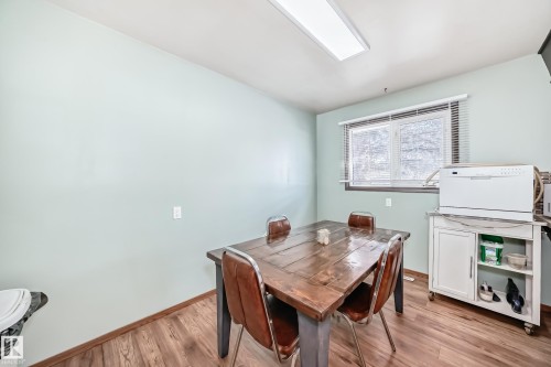 This room features wood-look flooring, light-colored walls, and a window with horizontal blinds - 4237 116 Avenue, Edmonton, AB - Indoor Photo Showing Dining Room