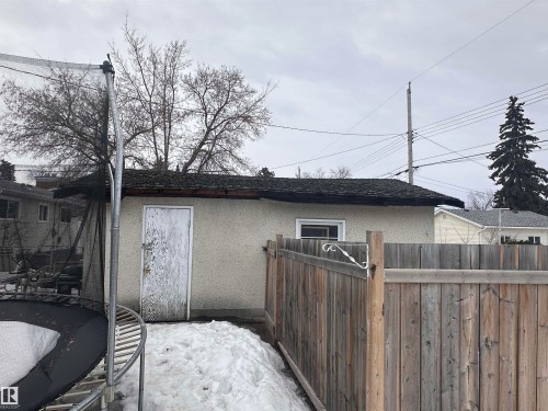 The property features an outbuilding with a wooden door and a window, surrounded by a wooden fence - 9724 102 Avenue, Westlock, AB - Outdoor