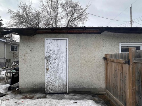 The property includes an exterior storage building with a light-colored stucco finish and a wooden fence - 9724 102 Avenue, Westlock, AB - Outdoor