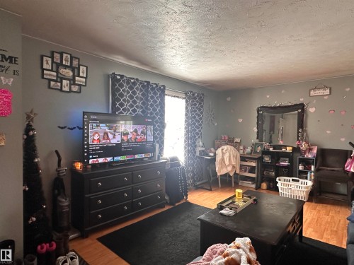 The living area features wood-look flooring and a window with patterned curtains - 9724 102 Avenue, Westlock, AB - Indoor