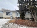 The property features a light-colored stucco exterior with a prominent front window and a light blue front door - 9724 102 Avenue, Westlock, AB  - Outdoor 