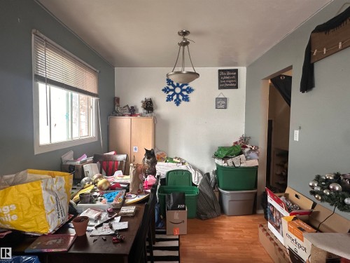 This room features a window with blinds, a ceiling light fixture, and wood-toned flooring - 9724 102 Avenue, Westlock, AB - Indoor Photo Showing Dining Room