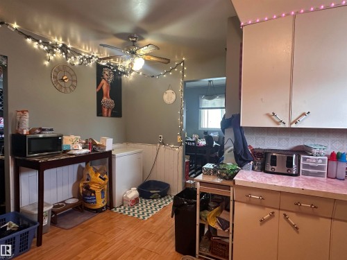 The kitchen features light-colored cabinetry, a textured backsplash, and a countertop with a pink and white pattern - 9724 102 Avenue, Westlock, AB - Indoor