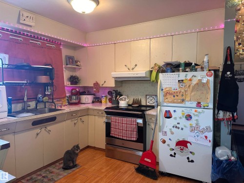 The kitchen features cream-colored cabinetry, a stainless steel oven, and a white refrigerator - 9724 102 Avenue, Westlock, AB - Indoor Photo Showing Kitchen