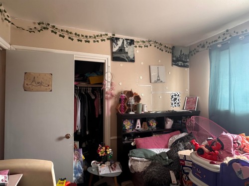 The property features a room with light-colored walls, a closet with a bi-fold door, and a window with blue curtains - 9724 102 Avenue, Westlock, AB - Indoor