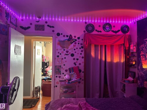 This room features ambient purple lighting, a wall decorated with heart and butterfly motifs, and windows draped with purple curtains - 9724 102 Avenue, Westlock, AB - Indoor