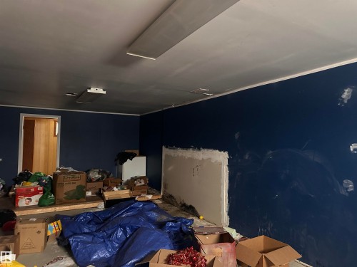 Room with dark blue walls, a white ceiling, and a doorway leading to a room with wood paneling - 9724 102 Avenue, Westlock, AB - Indoor