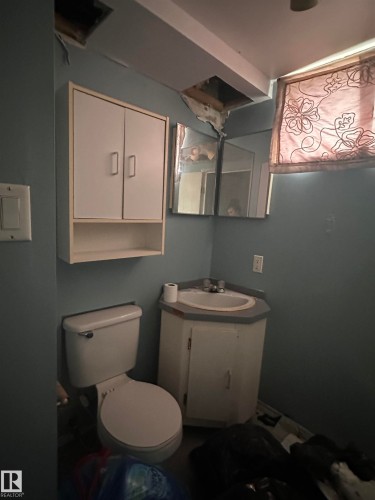 Bathroom featuring a toilet, a corner vanity with a sink, and a wall-mounted cabinet - 9724 102 Avenue, Westlock, AB - Indoor Photo Showing Bathroom