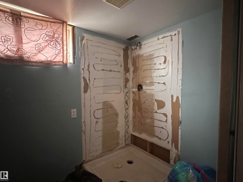 Bathroom featuring a shower stall with exposed wallboard and a small window - 9724 102 Avenue, Westlock, AB - Indoor Photo Showing Other Room