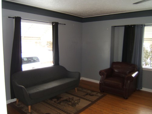 Living area featuring hardwood floors, gray walls, and large windows with dark curtains - 5023 50 Street, Two Hills, AB - Indoor