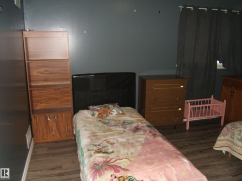 This room features wood-look flooring and dark-toned walls - 5023 50 Street, Two Hills, AB - Indoor Photo Showing Bedroom