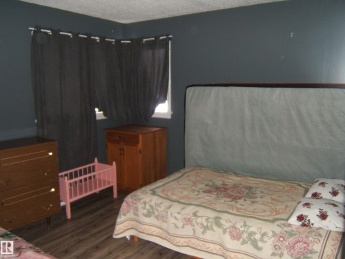 The room features dark walls and wood-style flooring - 5023 50 Street, Two Hills, AB - Indoor Photo Showing Bedroom