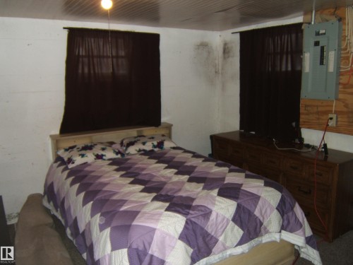 The property features a room with two windows, a light fixture, and a textured ceiling - 5023 50 Street, Two Hills, AB - Indoor Photo Showing Bedroom
