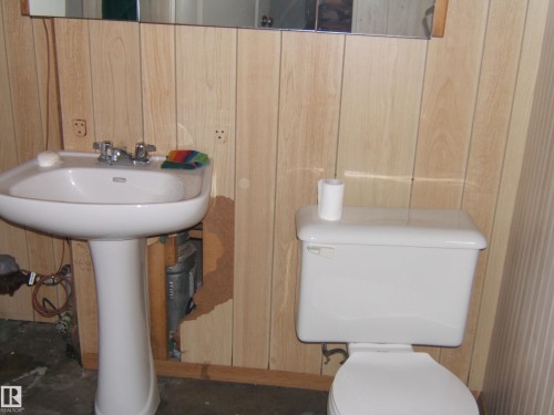 Bathroom featuring a white pedestal sink with a chrome faucet and a white toilet - 5023 50 Street, Two Hills, AB - Indoor Photo Showing Bathroom