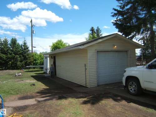 Detached garage featuring panel siding and a roll-up door - 5023 50 Street, Two Hills, AB - Outdoor
