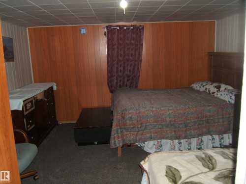 This room features wood paneling on the walls and a drop ceiling - 5023 50 Street, Two Hills, AB - Indoor Photo Showing Bedroom