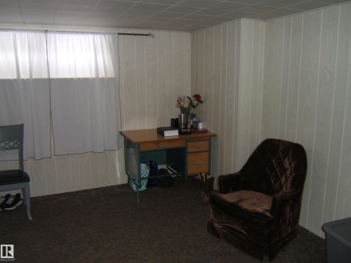 This room features light-colored wall paneling, a drop ceiling, and carpeted flooring - 5023 50 Street, Two Hills, AB - Indoor Photo Showing Other Room
