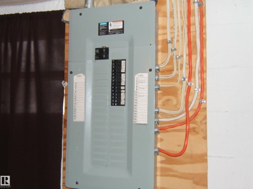 Electrical panel mounted on a wood-paneled wall, featuring clearly labeled circuits - 5023 50 Street, Two Hills, AB - Indoor Photo Showing Basement